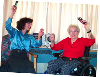 Sit'n'dance teacher and a lady in a wheelchair enjoing sit'n'dance group class